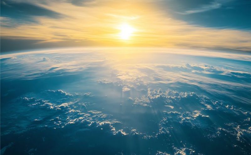 The earth from space, with the sun rising behind it