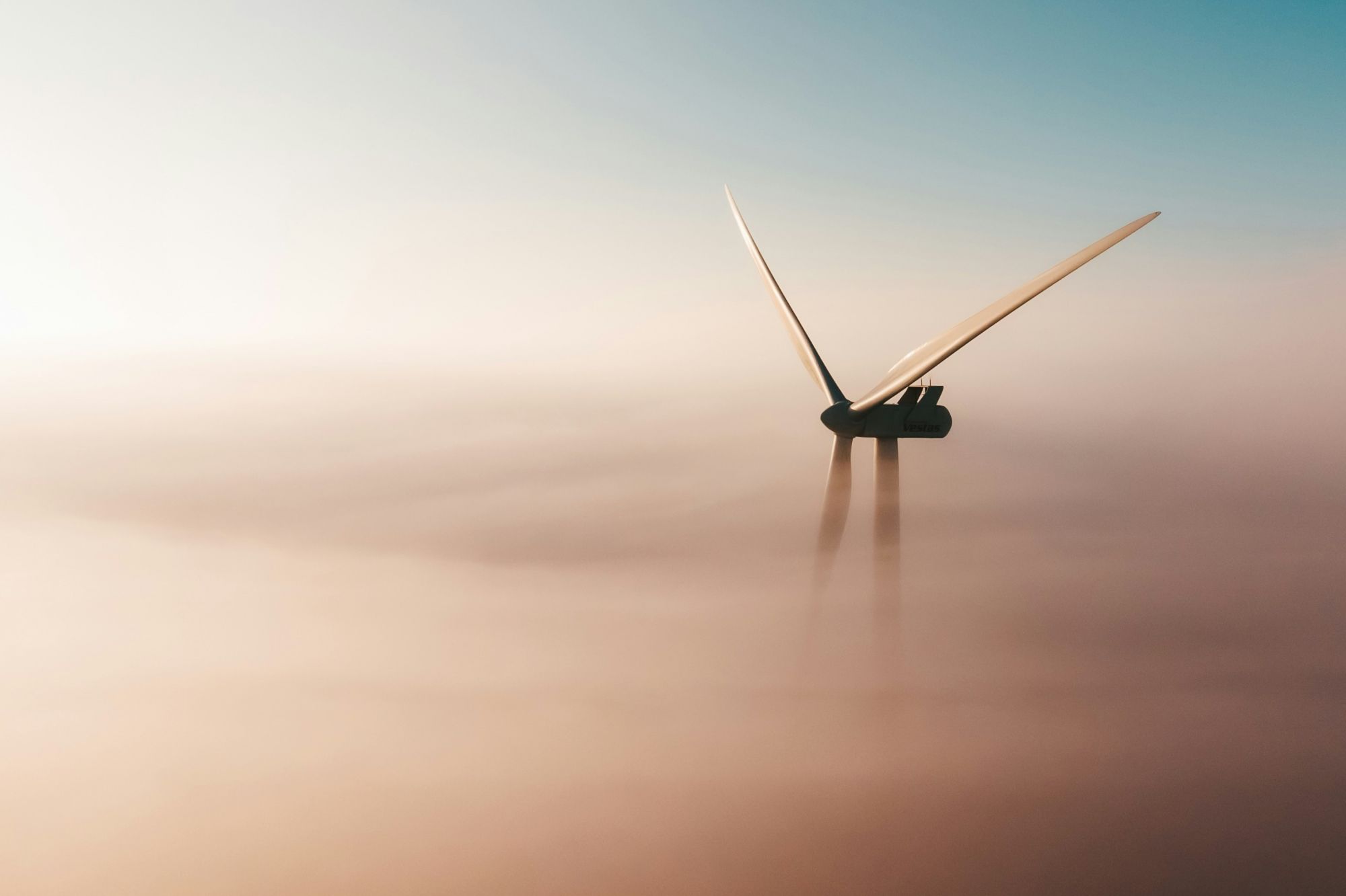 Wind turbine emerging above a cloud of fog